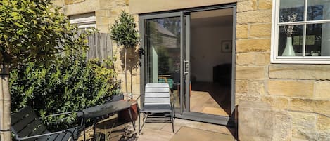 A stone building with a patio, a sliding glass door, and a bench.