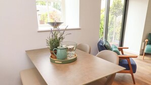 A dining area with a table, chairs, a bench, a potted plant, and a window with a view of greenery. - Snowdrop Cottage (Morpeth)