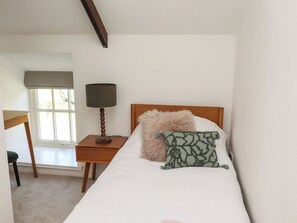 Une chambre à coucher avec un lit, une table de chevet, une lampe, une chaise et une fenêtre.