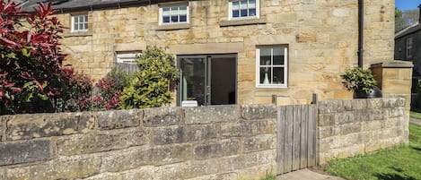 A stone building with a wooden fence, a door, and a window.