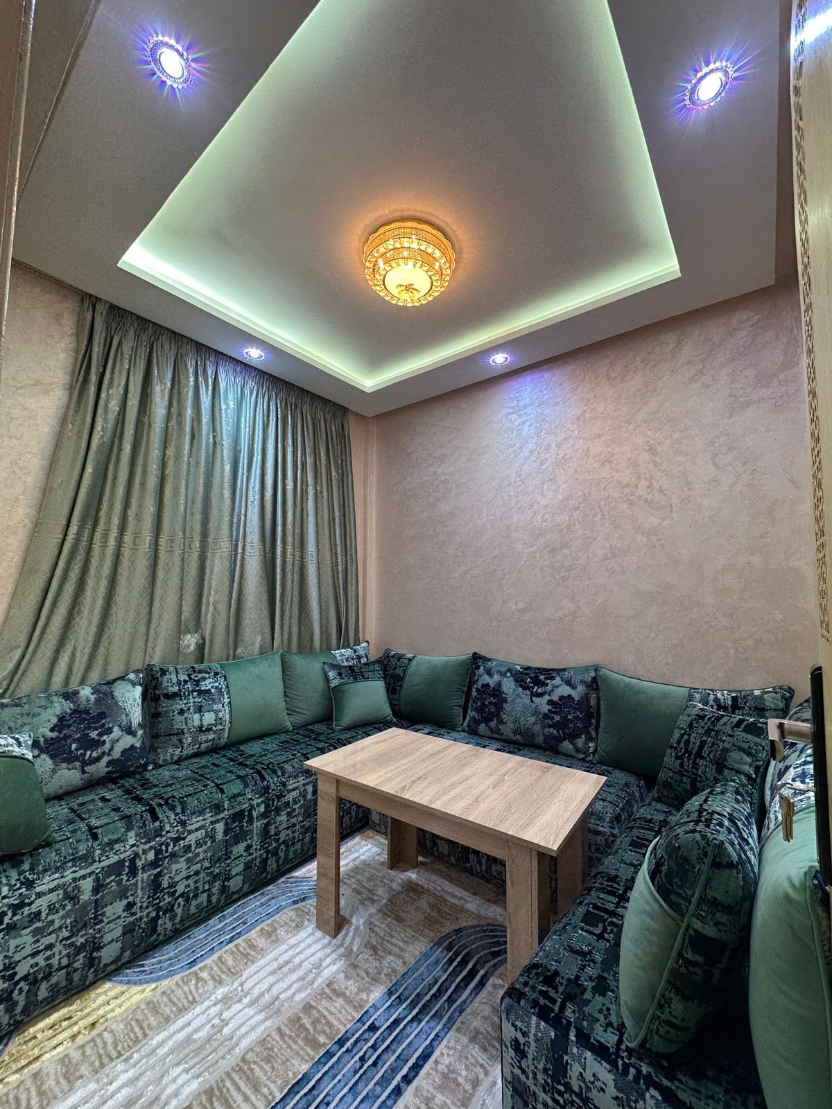 A modern living room with a sectional sofa, a wooden coffee table, and a ceiling light fixture.