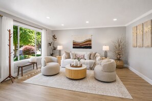A living room with a sofa, two armchairs, a coffee table, and a large window.