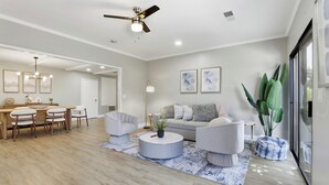 Uma sala de estar moderna com uma mesa de centro redonda, um sofá e uma área de jantar com cadeiras e uma mesa.