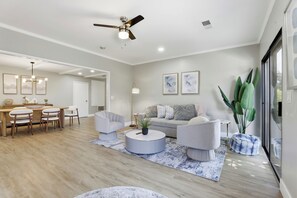 A modern living room with a round coffee table, a sofa, and a dining area with chairs and a table.