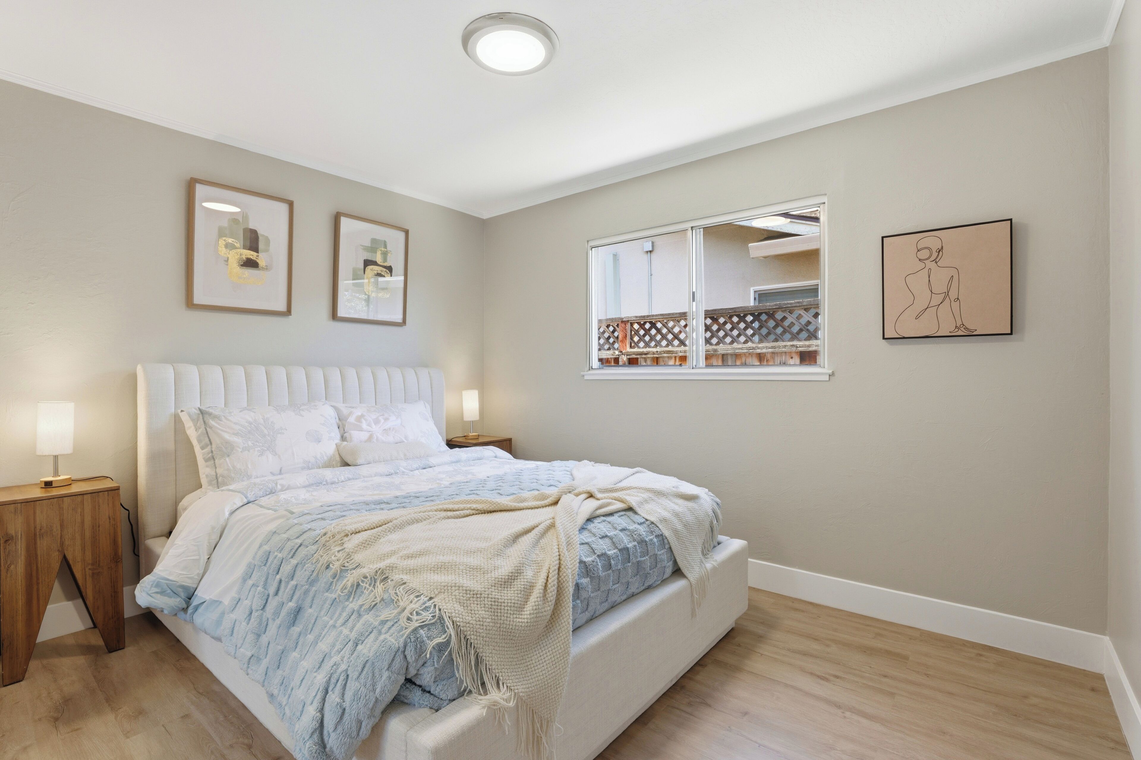 A bedroom with a bed, bedside tables, and wall art.