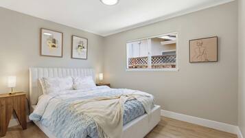A bedroom with a bed, bedside tables, and wall art.