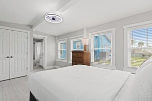 Un dormitorio con cama, armario blanco y mesita de mimbre con lámpara.