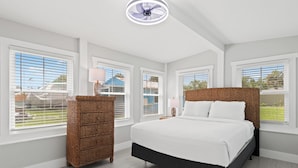 A bedroom with a large bed, a wicker dresser, and a ceiling fan. - Beach House - St Joe Retreat (Port St. Joe)