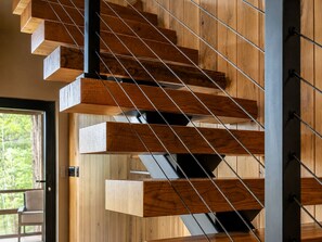 A modern staircase with wooden steps and metal railings. - Luxury Treehouse Retreat | Bordering Gorges (Brevard)