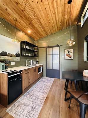 Een moderne keuken met houten kastjes, een inbouwoven, een vaatwasser en een eethoek met een tafel en stoelen.