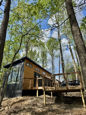 Eine Hütte mit einer Terrasse, umgeben von Bäumen.
