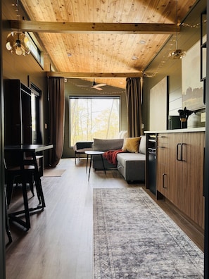 Een modern interieur met een houten plafond, een bank, een eettafel en een keukenhoek.
