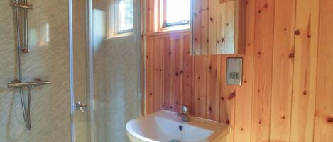 Ein Badezimmer mit Duschkabine aus Glas, Waschbecken und Toilette.