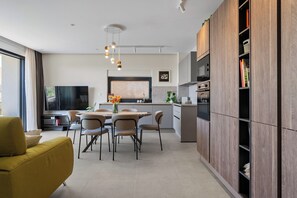 A modern kitchen with a dining area, a TV, and wooden cabinets. - Beautiful 3-bedroom apartment with AC in charming Kaštel Stari (Kaštel Stari)