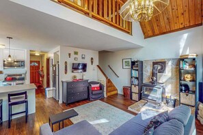 A spacious living area with a kitchen, dining area, and a fireplace. - Cazadero 2BR creekside cottage — fenced yard, dogs welcome (Cazadero)
