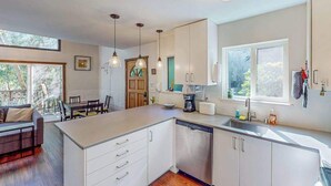 Une cuisine moderne avec des meubles blancs, un lave-vaisselle et un coin repas comprenant une table et des chaises.
