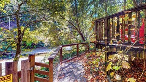 Un pont en bois, agrémenté d’un panneau d’avertissement, entouré d’un feuillage automnal.