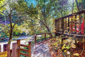 A wooden bridge with a caution sign, surrounded by autumn foliage. - Cazadero 2BR creekside cottage — fenced yard, dogs welcome (Cazadero)
