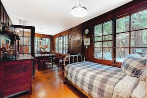 A room with a bed, a desk, a chair, and large windows. - Guerneville Clearheart Grove: Dog-Friendly Redwood Cabin (Guerneville)