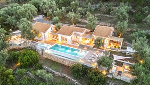 Eine Villa mit Schwimmbad, mehreren Sitzbereichen im Freien und einem Kiesweg.