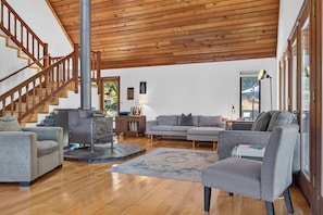 A spacious living area with a wooden staircase, a fireplace, a sofa, and a coffee table. - Sebastopol 4BR hilltop home with hot tub, wood stove & game room, dogs welcome (Sebastopol)