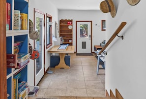 A hallway with a wooden staircase, a door with a window, and a table with a board game. - Sebastopol 4BR hilltop home with hot tub, wood stove & game room, dogs welcome (Sebastopol)