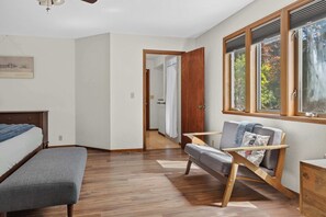 A room with a bed, a chair, a window with blinds, and a door leading to another room. - Sebastopol 4BR hilltop home with hot tub, wood stove & game room, dogs welcome (Sebastopol)