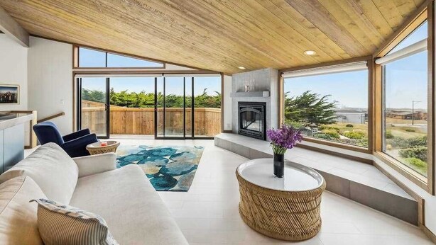 A spacious living area with a fireplace, large windows, and a view of greenery. - Architect-Designed Bodega Bay Home w/ Ocean Views & Hot Tub - 2 King Suites (Bodega Bay)