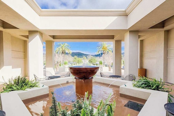 A courtyard with a central water feature, seating areas, and a view of palm trees and mountains. - Napa 2BR Silverado condo — two king suites, golf views & pool (Napa)