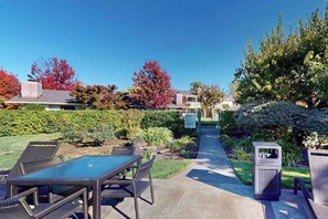 A patio with outdoor furniture, a pathway, and a trash bin. - Napa Silverado studio, freshly updated, with fenced patio & pool (Napa)