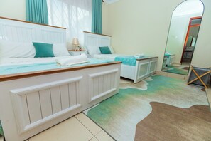 A bedroom with two beds, a mirror, and a bathroom visible in the reflection. - Modern Cozy 2 bedroom Retreat with Private balcony (Kampala)