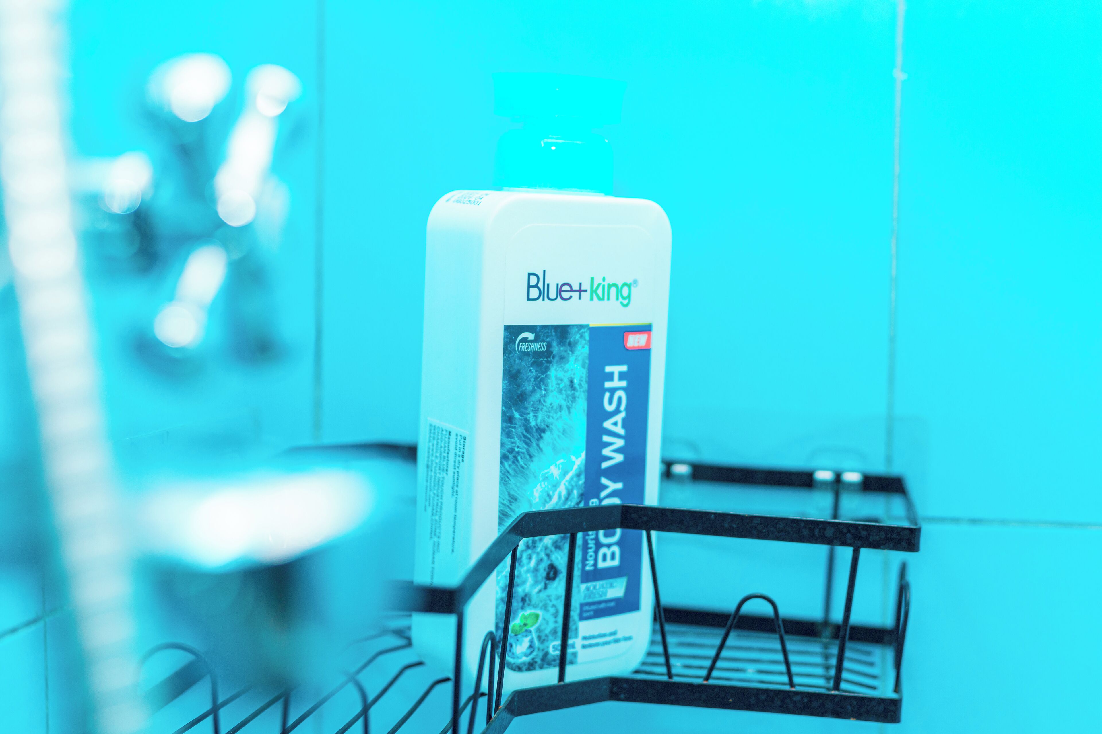 Une bouteille de gel douche Blue+King sur un étagère métallique dans une salle de bain.