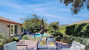 Une terrasse avec des chaises longues, une piscine et un jardin bien entretenu.