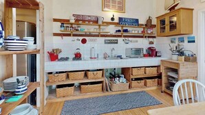 Una cucina con scaffali in legno, zoccolo di piastrelle bianche e un cartello che indica ostriche fresche.