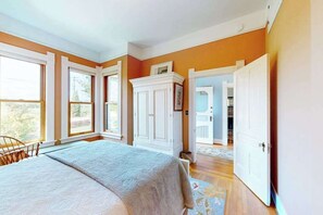 Ein Schlafzimmer mit Bett, Kleiderschrank und einer Tür zu einem weiteren Raum.