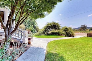 A residential property with a well-maintained lawn, a curved driveway, and a wooden fence.