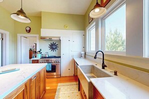 A kitchen with wooden cabinets, a stove, a sink, and a window.