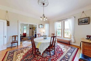 Ein Esszimmer mit einem runden Tisch, Stühlen, einer Chandelier und einem großen, gemusterten Teppich.