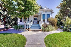 A two-story house with a front porch, a staircase leading to the entrance, and a well-maintained lawn.