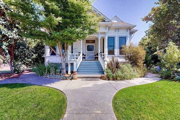 A two-story house with a front porch, a staircase leading to the entrance, and a well-maintained lawn.