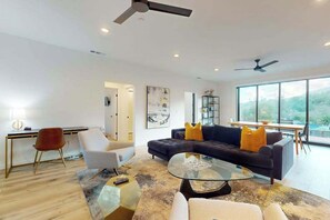 A modern living room with a sectional sofa, a glass coffee table, and a desk with a chair.