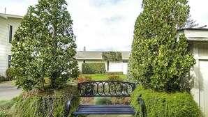Un sentier qui mène à un banc entouré de haies et d’arbres bien entretenus.