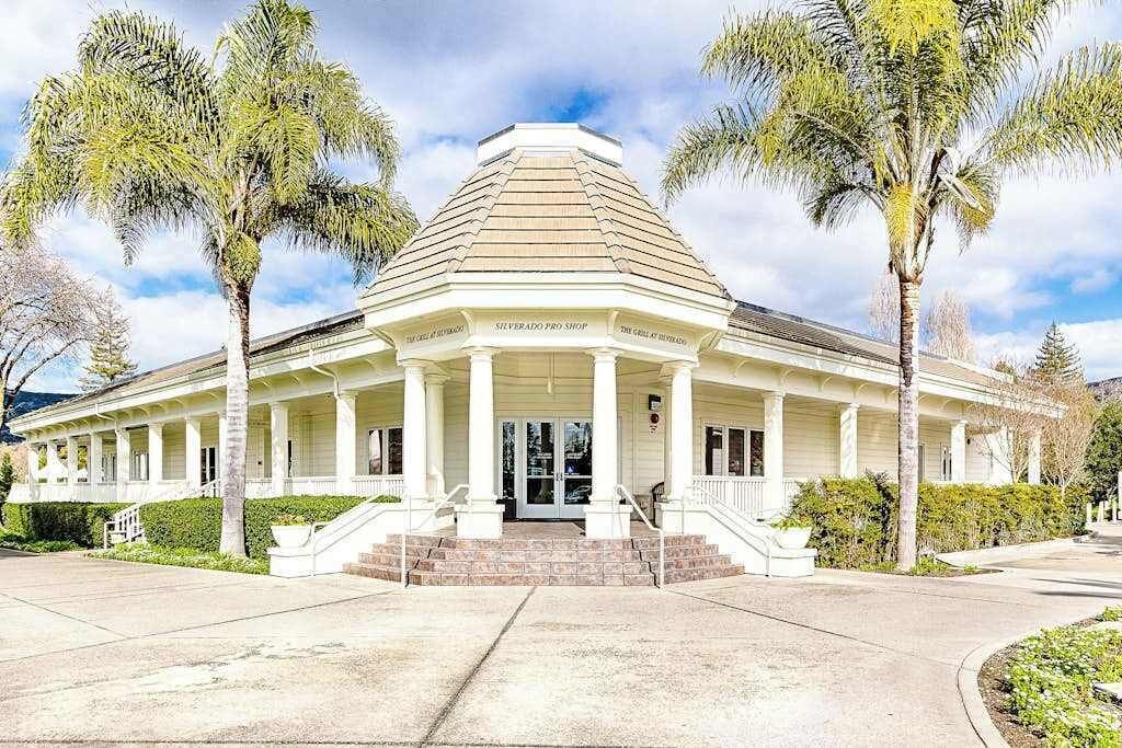 A two-story building with a central entrance, columns, and a sloped roof.