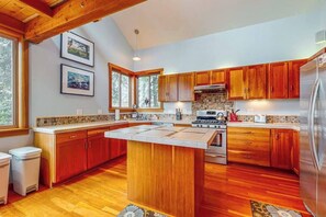 Una cocina con armarios de madera, una isla central, una estufa y un refrigerador.