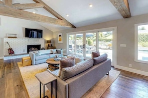 A spacious living area with a fireplace, a sofa, a coffee table, and a television.