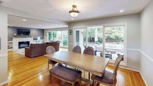 A spacious dining area with a wooden table and chairs, a fireplace, and a view of the outdoors through large windows. - Renovated Wine Country Ranch w/ Private Patio & AC - Sleeps 4 in Santa Rosa (Santa Rosa)