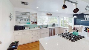 A modern kitchen with white cabinetry, a central island, a stove, and a window with a view. - Renovated Wine Country Ranch w/ Private Patio & AC - Sleeps 4 in Santa Rosa (Santa Rosa)