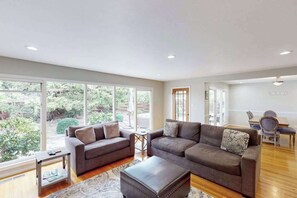 A spacious living room with large windows, a sofa set, a coffee table, and a dining area. - Santa Rosa Renovated Home with Fireplace & Private Patio (Santa Rosa)