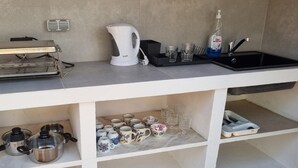 A kitchenette with a coffee maker, kettle, and sink. There are cups and glasses on the counter. - Peaceful Beautiful Countryside Perfect Destination (Tavira)