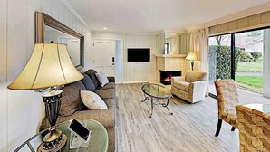 A living room with a sofa, armchairs, a glass coffee table, a fireplace, and a TV mounted on the wall. - Napa 2BR Silverado condo — two king suites, fireplace & pool (Napa)